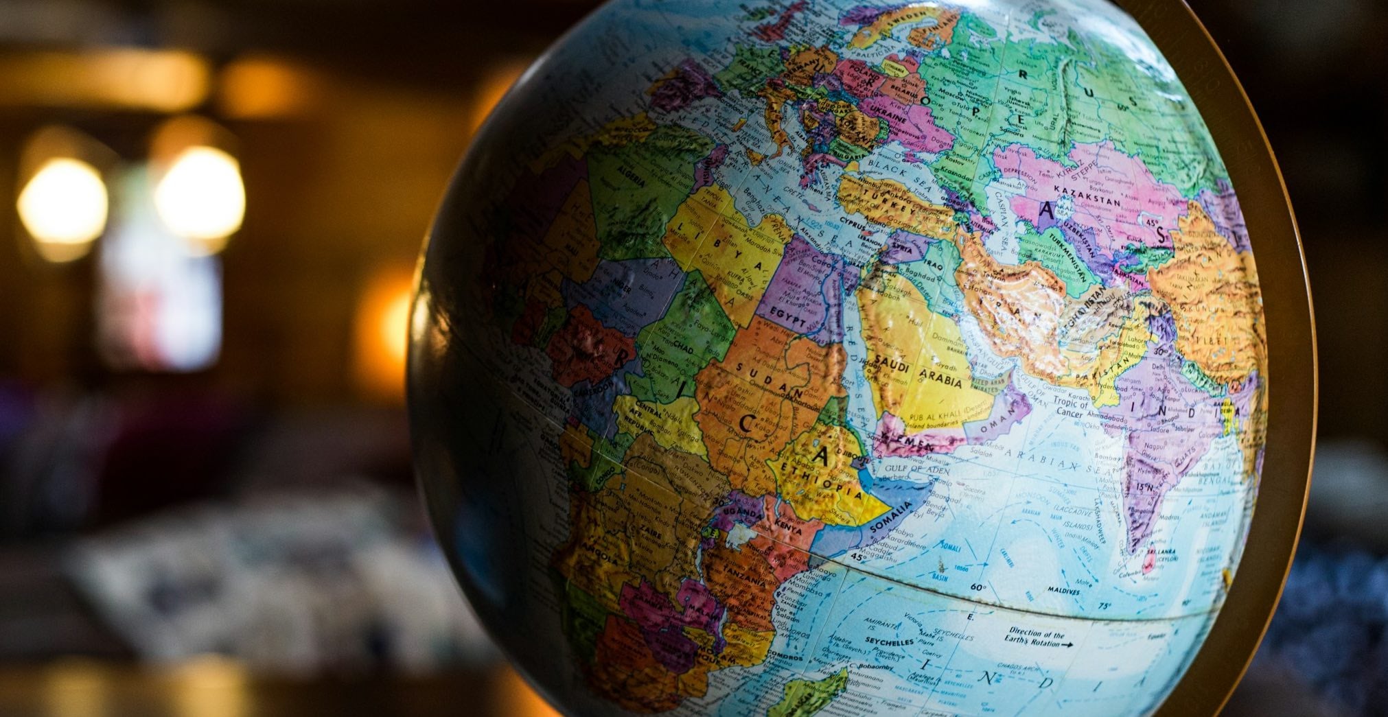 A globe on a desk showing Africa, Europe, India. The background is blurred and glowing.